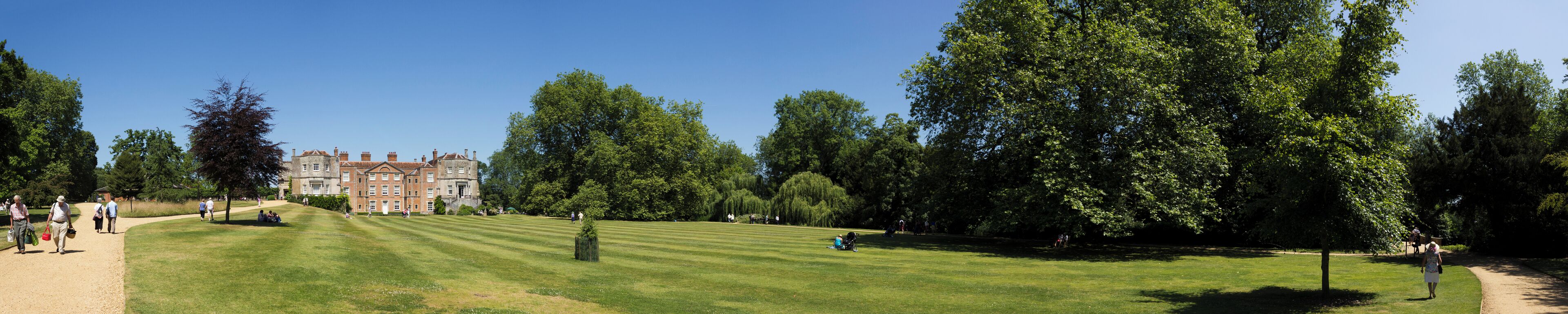 A well-manicured lawn, a large tree, and a historic building in the background.