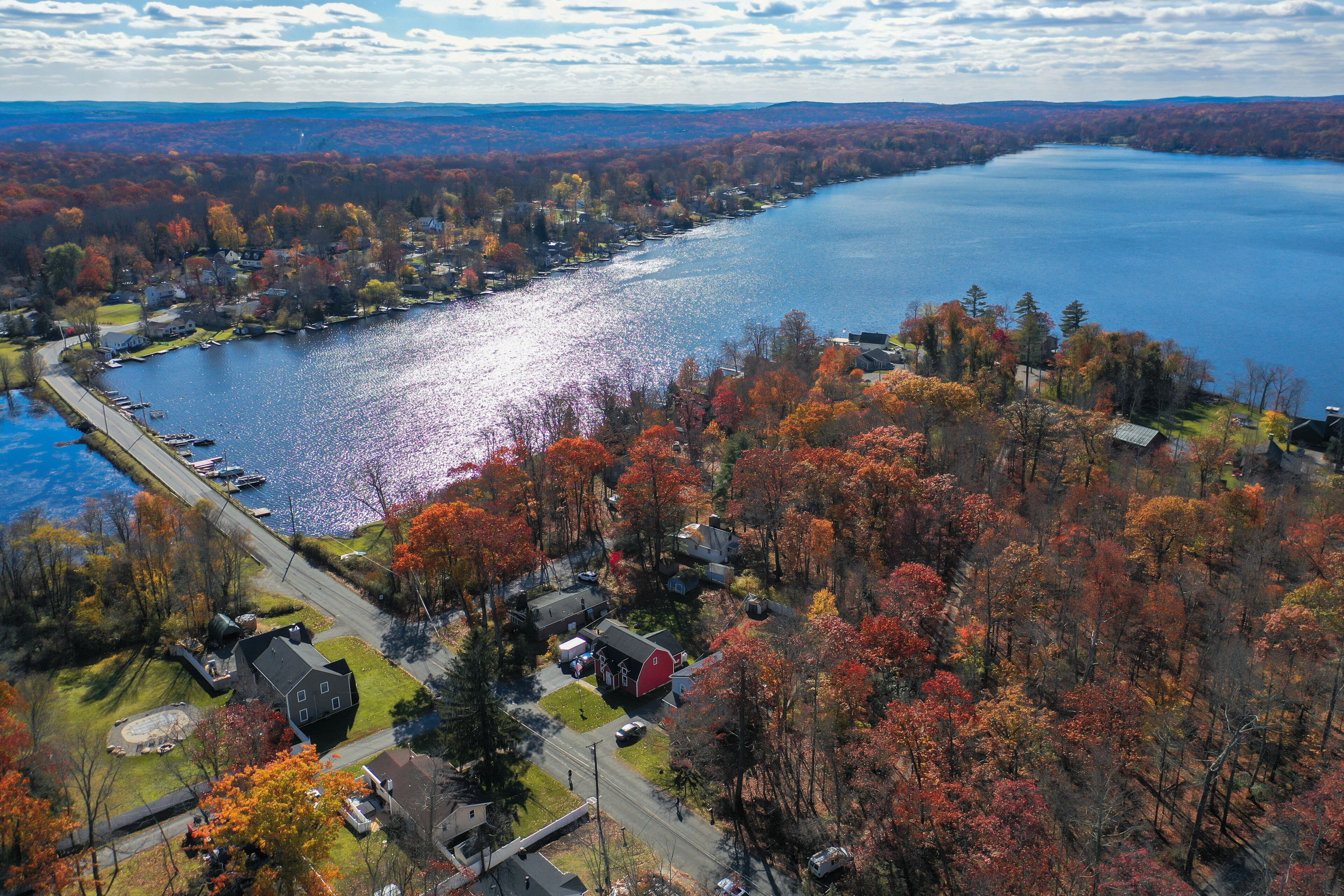 An aerial view of a lakeside community with autumn foliage, houses, and a dock.