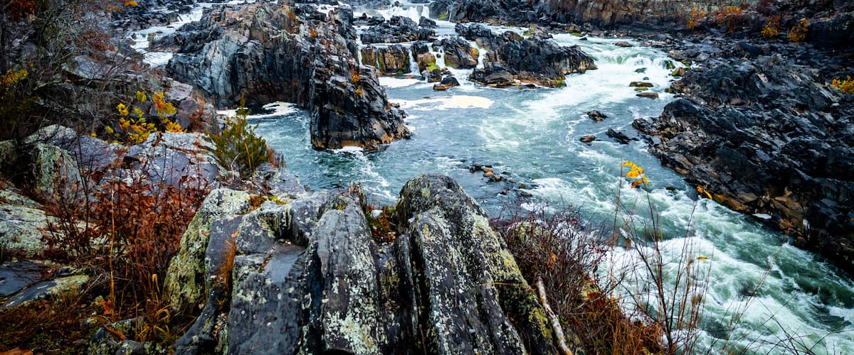 A river flowing through a rocky landscape with autumn foliage.