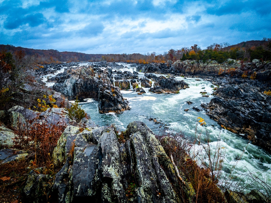 A river flowing through a rocky landscape with autumn foliage.