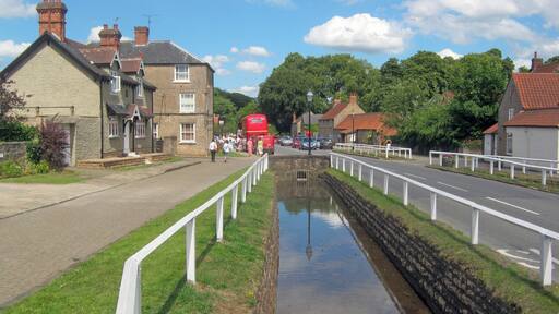 Main Street at Linby, Nottinghamshire. Looking north-east down the length of Main Street, which has attractively fenced leats either side, giving it a head start in frequently winning the most attractive village in Nottinghamshire competitions. On this particular Sunday the village gardens are open as part of the National Gardens Scheme and there are various other attractions, including a Routemaster double-decker.