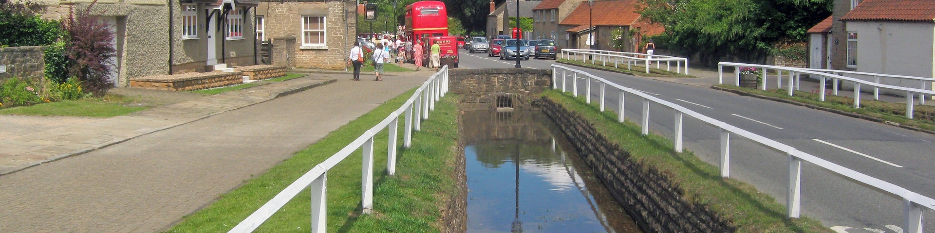 Main Street at Linby, Nottinghamshire. Looking north-east down the length of Main Street, which has attractively fenced leats either side, giving it a head start in frequently winning the most attractive village in Nottinghamshire competitions. On this particular Sunday the village gardens are open as part of the National Gardens Scheme and there are various other attractions, including a Routemaster double-decker.