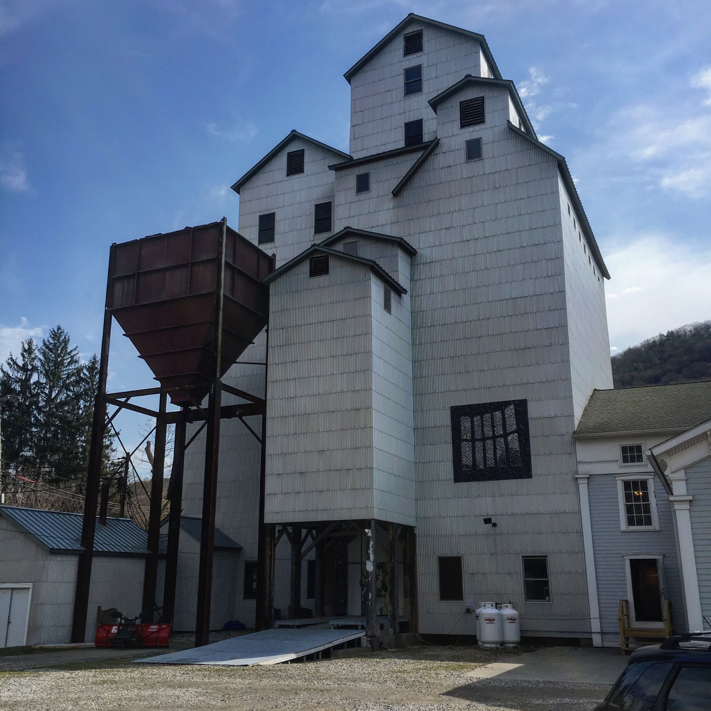A large industrial building with a silo-like structure and a smaller attached building.