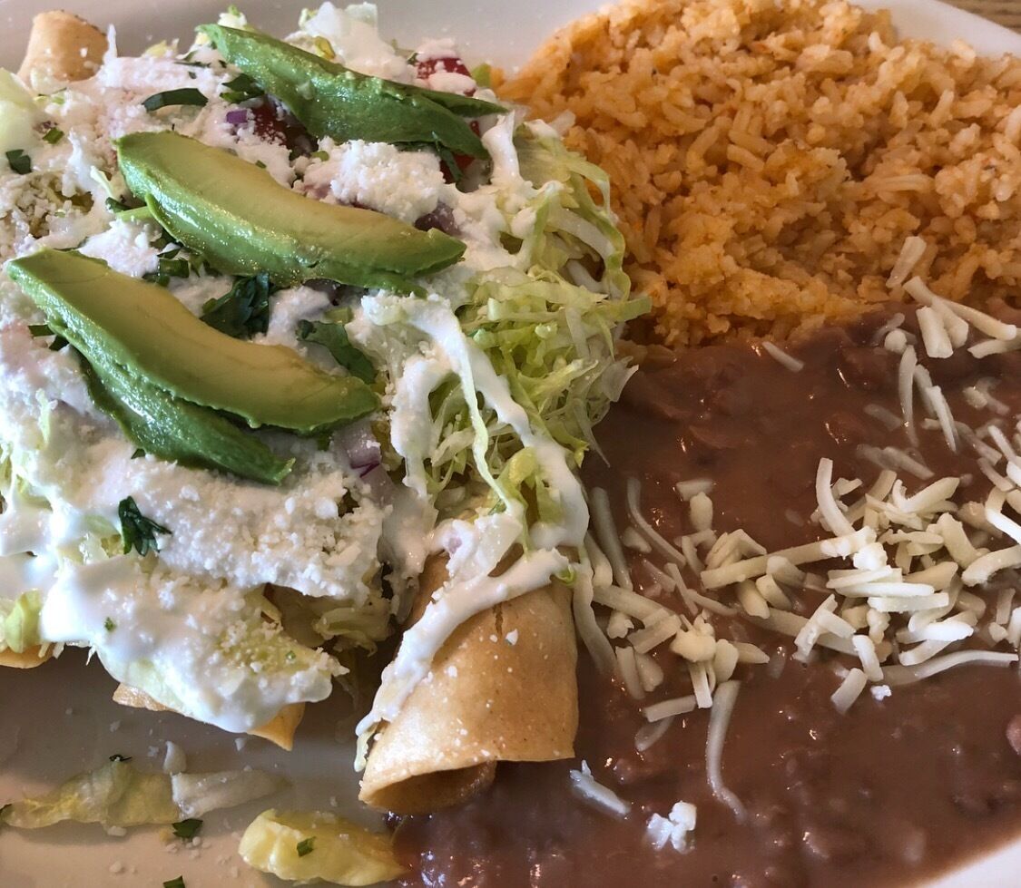 A plate with enchiladas, refried beans, and rice.