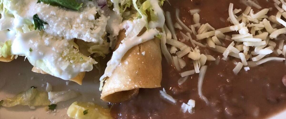 A plate with enchiladas, refried beans, and rice.