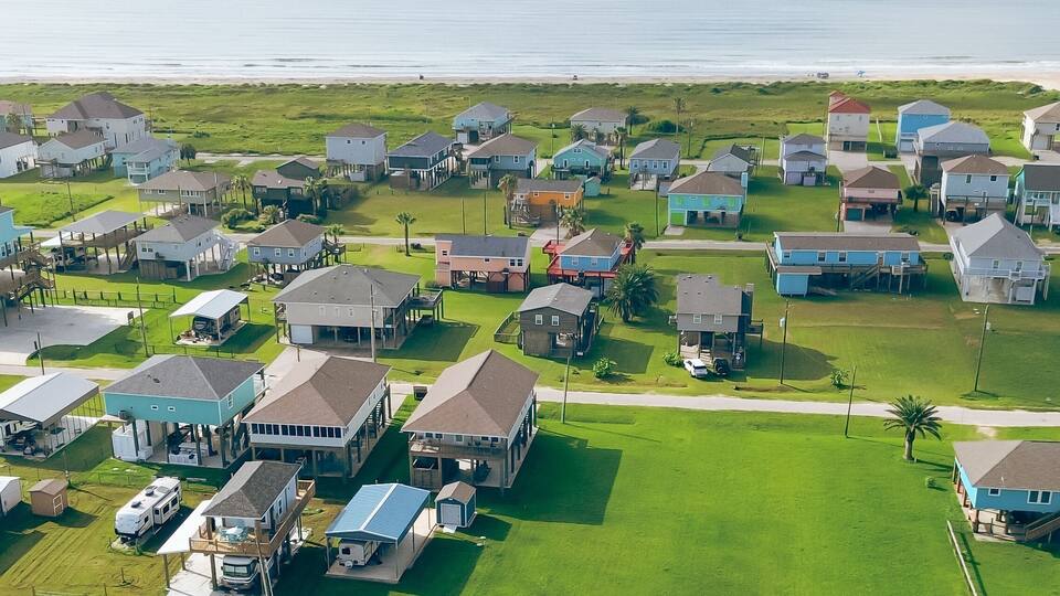 A coastal residential area with houses and a beach in the background.