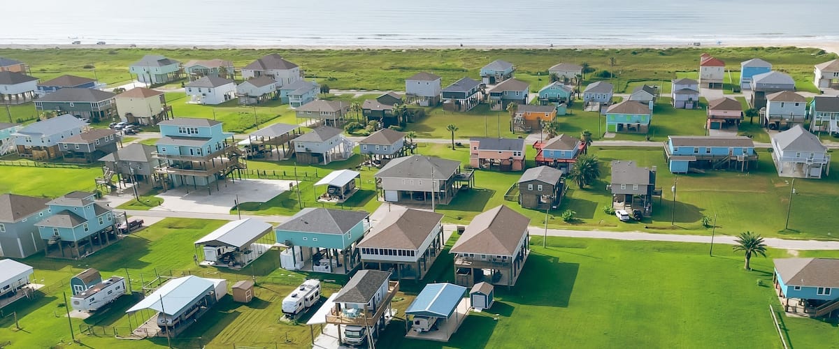 A coastal residential area with houses and a beach in the background.