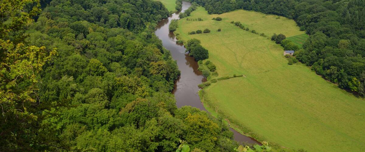 Un río serpentea por un valle exuberante, flanqueado por densos bosques.