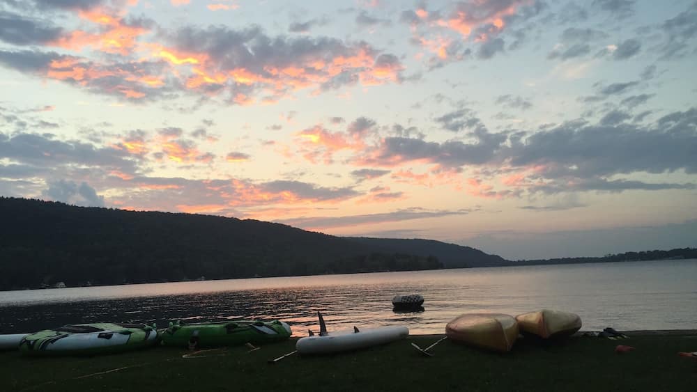 Ein Sonnenuntergang über einem See mit Booten am Ufer.