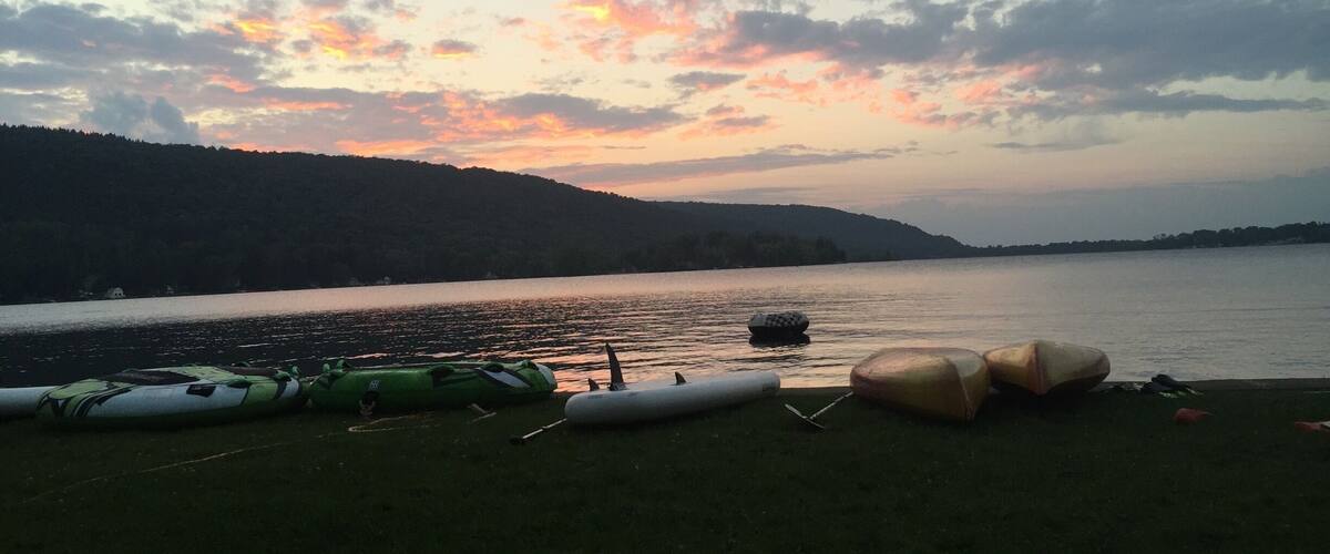 A sunset over a lake with boats on the shore.
