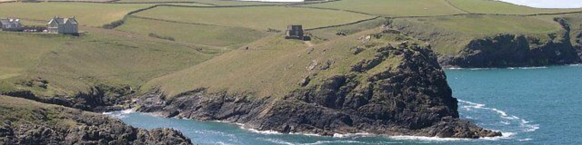 Across the entrance to Port Quin. The entrance to the old harbour of Port Quin is a narrow inlet. Across the other side at the centre of this photograph is Doyden Point on which stands Doyden Castle, an early example of a second home in Cornwall, built in 1830.
