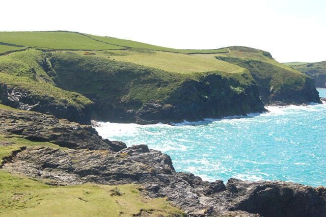 Un paysage côtier avec des collines verdoyantes et des falaises rocheuses au bord de la mer.