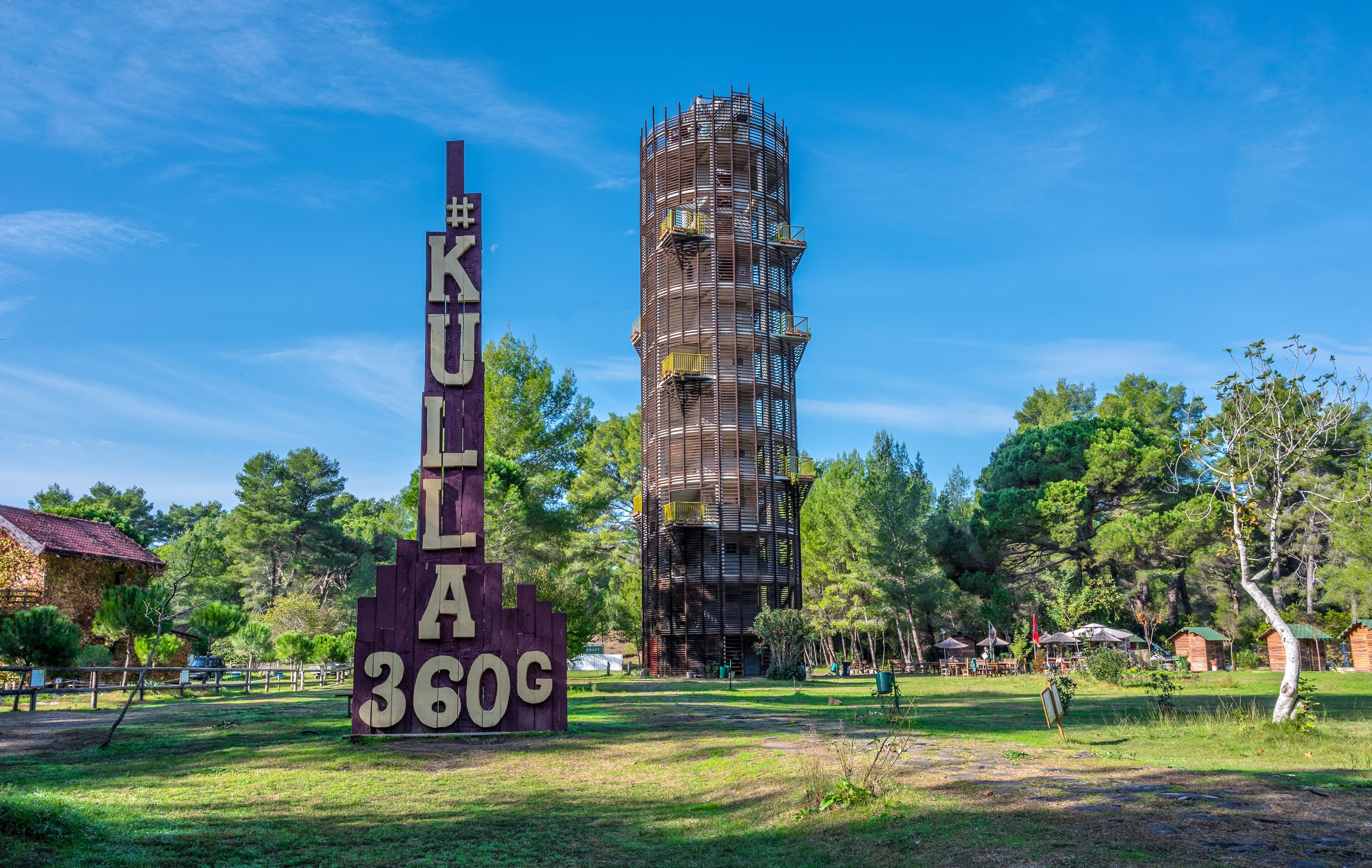 A tall, unfinished building with scaffolding, surrounded by trees and a sign reading "KULIA 360G".