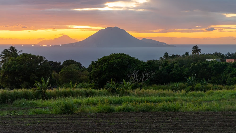 A sunset over a coastal landscape with a prominent mountain in the background.