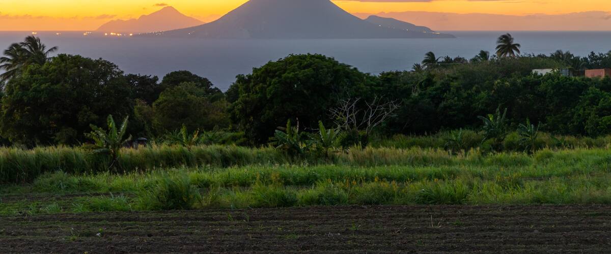 A sunset over a coastal landscape with a prominent mountain in the background.