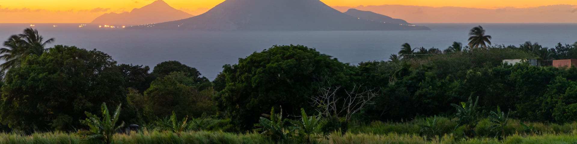 A sunset over a coastal landscape with a prominent mountain in the background.