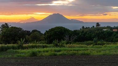 Un atardecer sobre un paisaje costero con una montaña destacada al fondo.