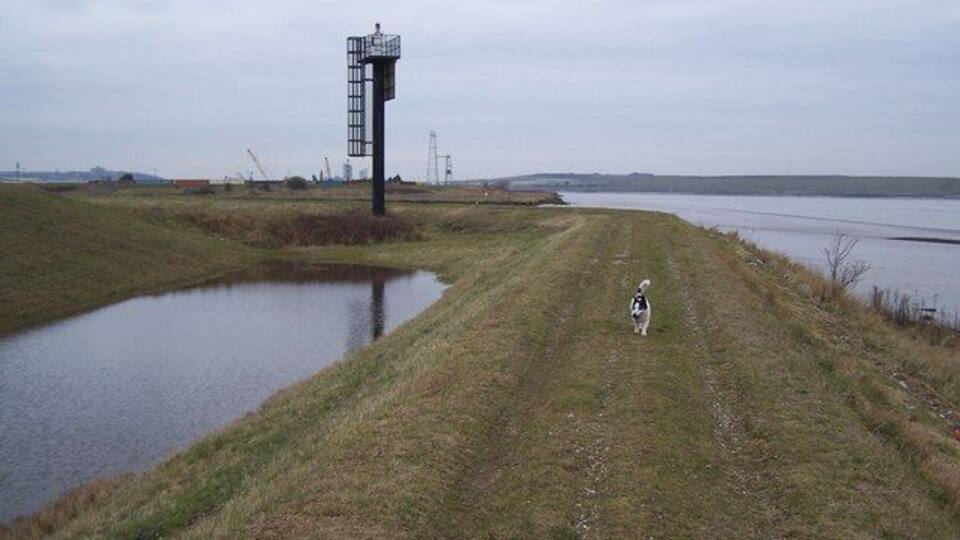 Sea wall and warning light Sea wall reaches River Darent/Dartford Creek entrance to River Thames. The warning light has a sign facing into the river. Which reads ' Warning. When this red light is flashing the creek flood barrier is closed and vessels will be unable to pass through'. The flood barrier is further to the left down the creek.