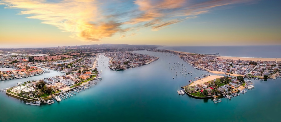 A coastal cityscape with a river, marina, and beach.