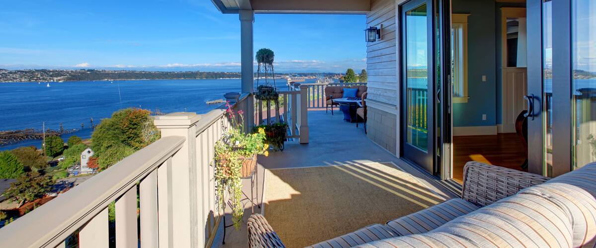 A balcony with a view of the ocean and a cityscape.