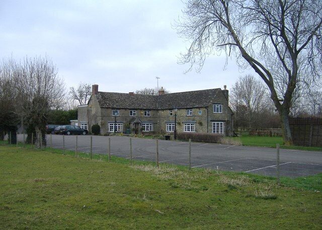 A stone building with a large driveway and a fenced sports court.