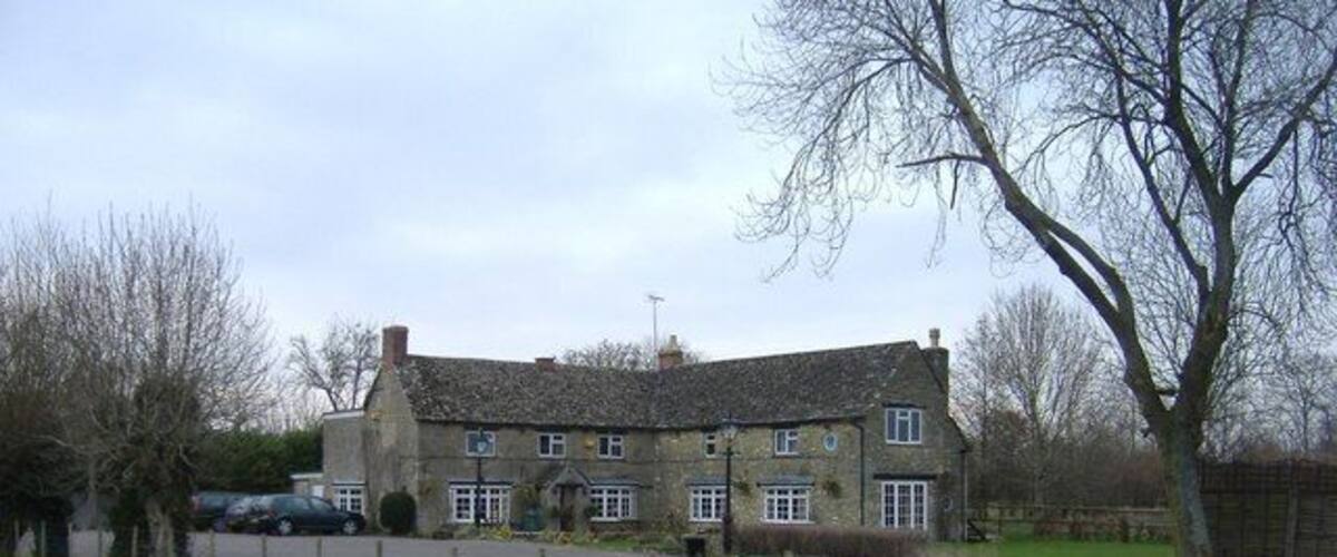 A stone building with a large driveway and a fenced sports court.