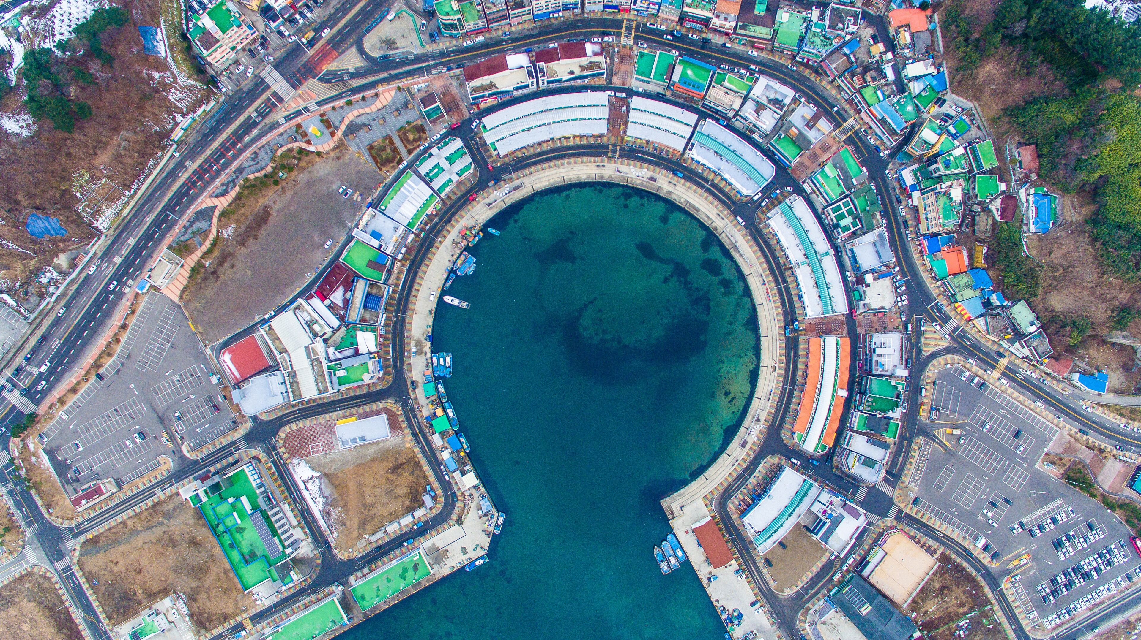 An aerial view of a coastal urban area with a large marina, roads, and buildings.