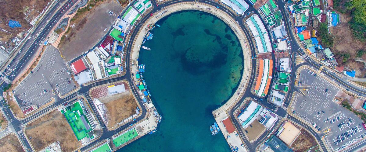 An aerial view of a coastal urban area with a large marina, roads, and buildings.