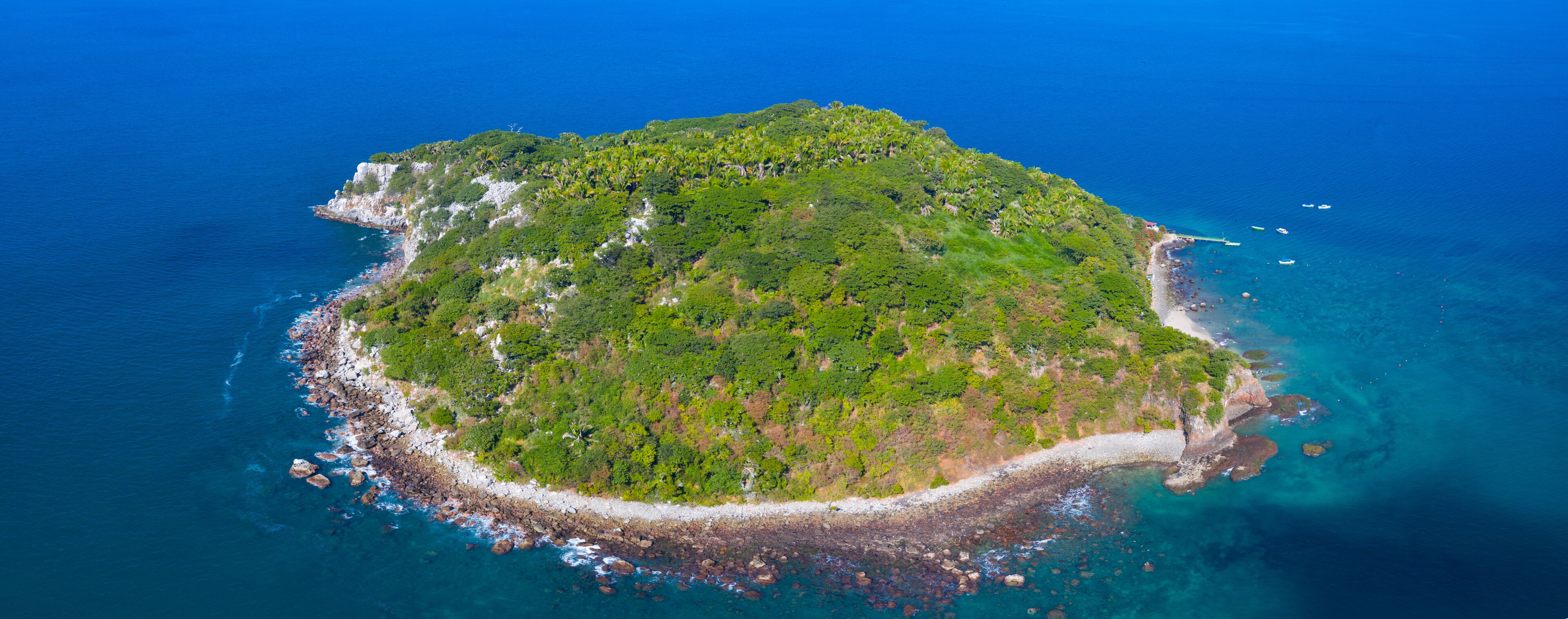 An aerial view of a lush, green island surrounded by clear blue waters.