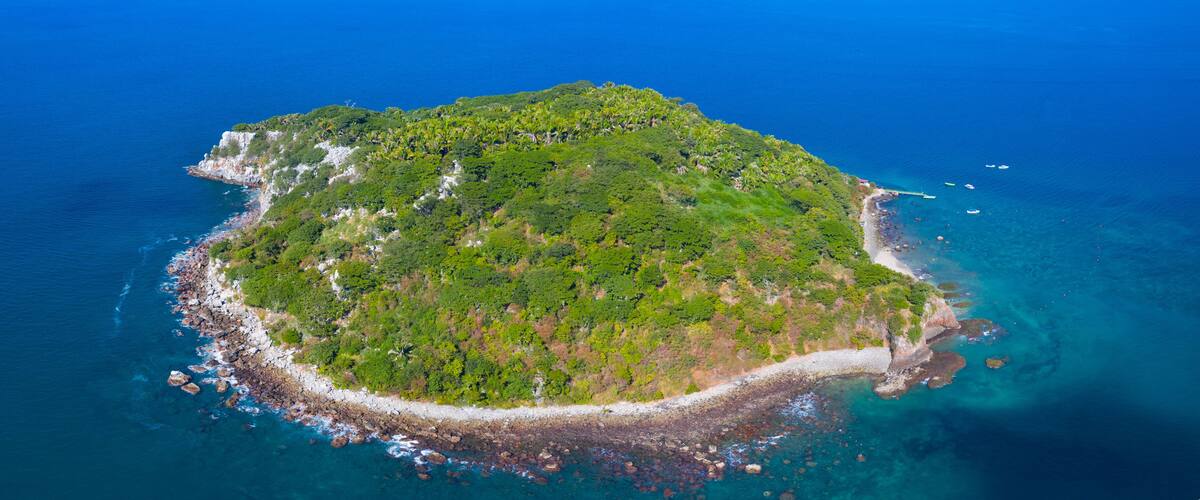 An aerial view of a lush, green island surrounded by clear blue waters.