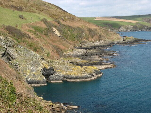 A coastal landscape with rocky cliffs and a calm sea.