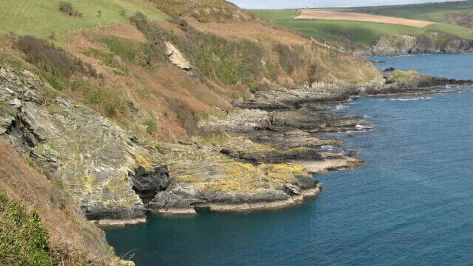 A coastal landscape with rocky cliffs and a calm sea.