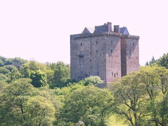 A medieval stone castle surrounded by lush green trees.