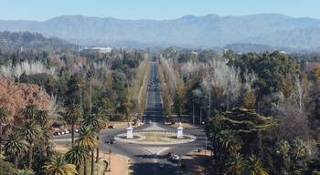 Aerial drone view of the entrance to Parque General San Martín in Mendoza, Argentina, with the Andes mountains visible in the background and the park landscape beautifully showcased