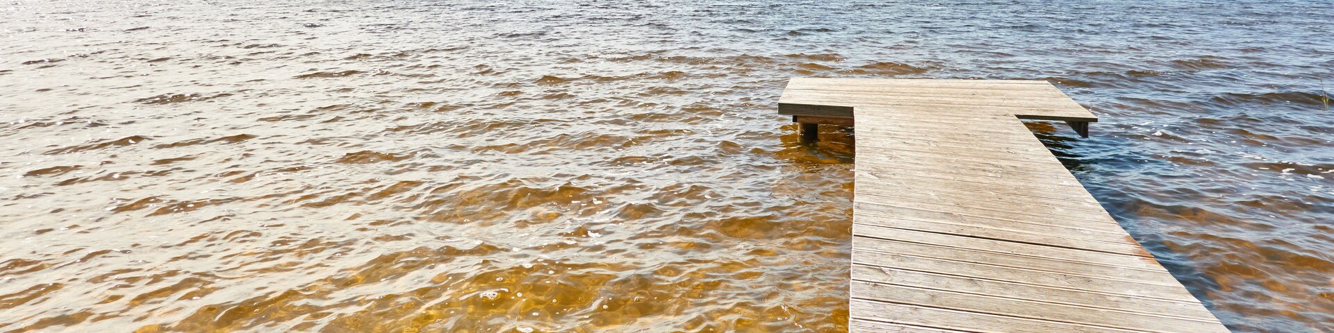 Forest river (lake) on a sunny day. Wooden pier. Clea sky, reflections in a crystal clear water. Idyllic landscape, rural scene. Nature, ecology, ecotourism, hiking, ecological resort, local tourism