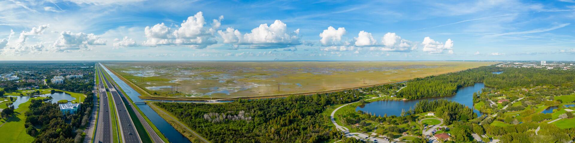 A coastal landscape with a highway, a river, and a lake surrounded by greenery.