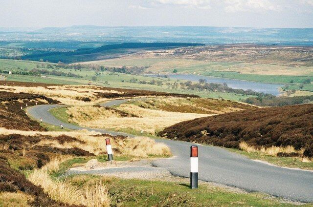 A line of red, white and black posts ...lead down towards Roundhill Reservoir.
