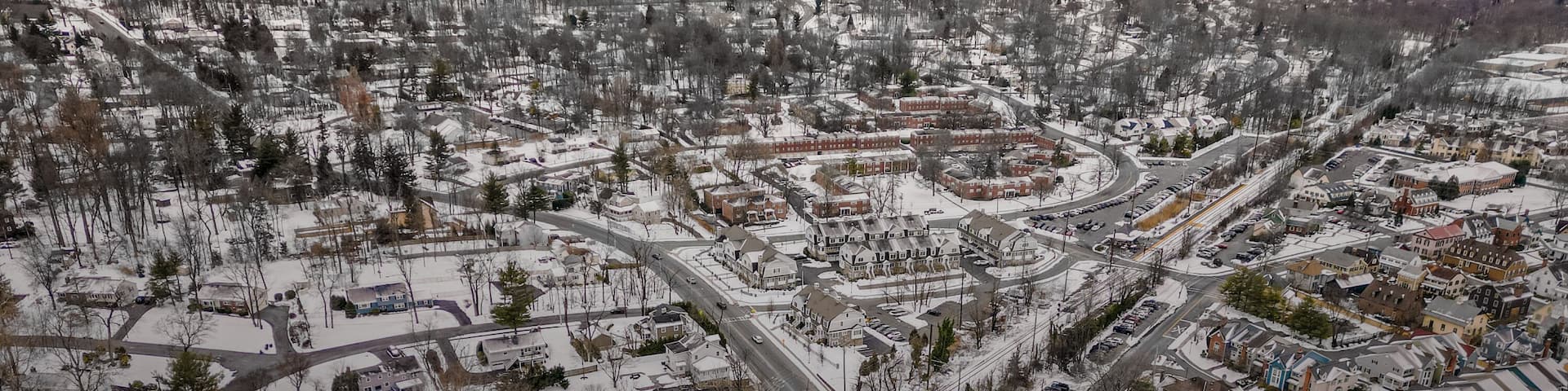 Aerial drone view of New Providence, New Jersey, covered in snow. The frozen landscape highlights roads, homes, and infrastructure, showcasing the suburban town in the cold season.
