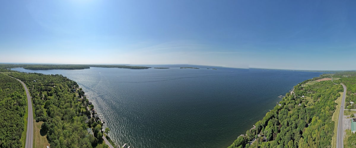 A large body of water surrounded by dense forests and a winding road.