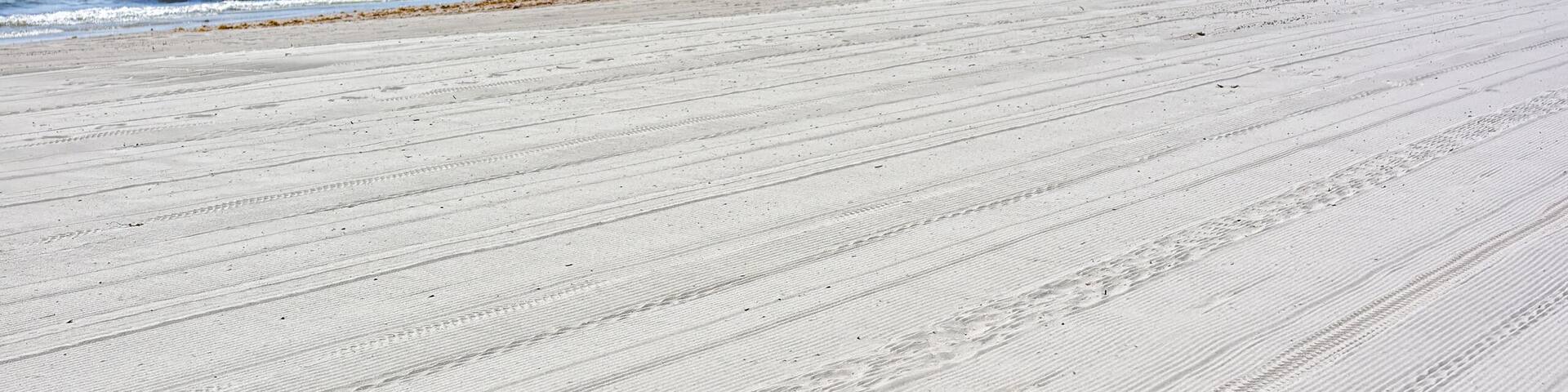 A sandy beach with footprints leading to the water.