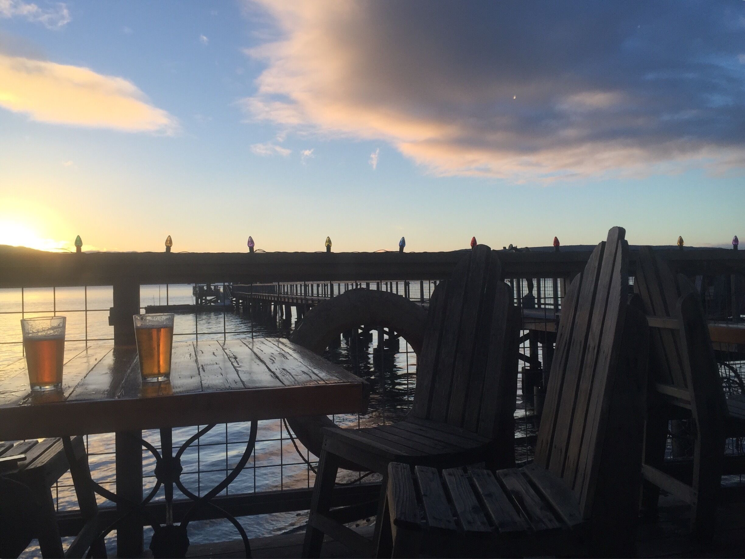 A wooden pier extending into a body of water during sunset.
