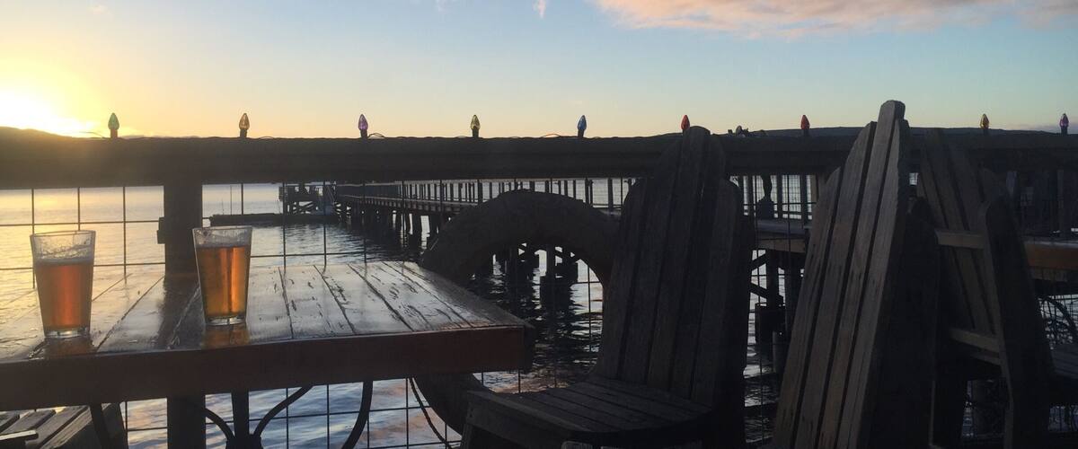 A wooden pier extending into a body of water during sunset.