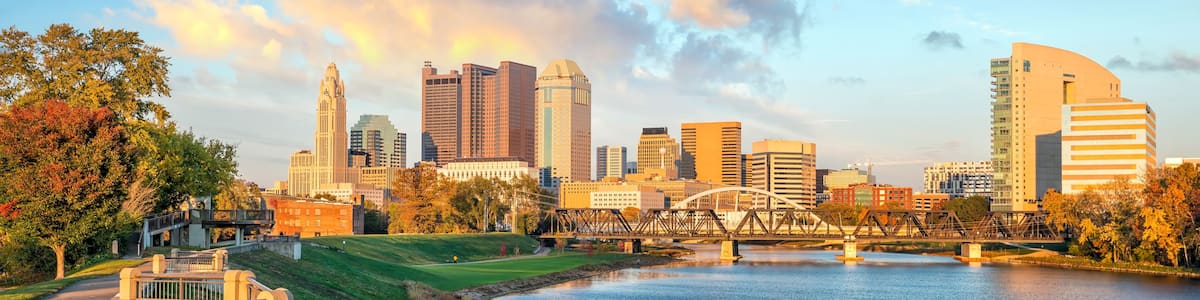 A city skyline with modern buildings, a river, and a bridge.