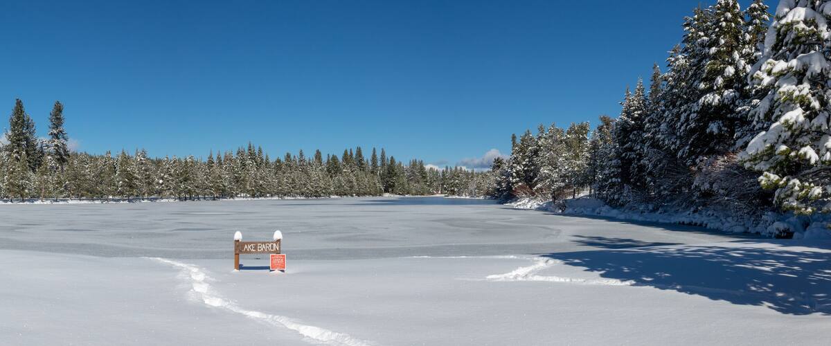 A snow-covered landscape with a sign for Lake Baron.