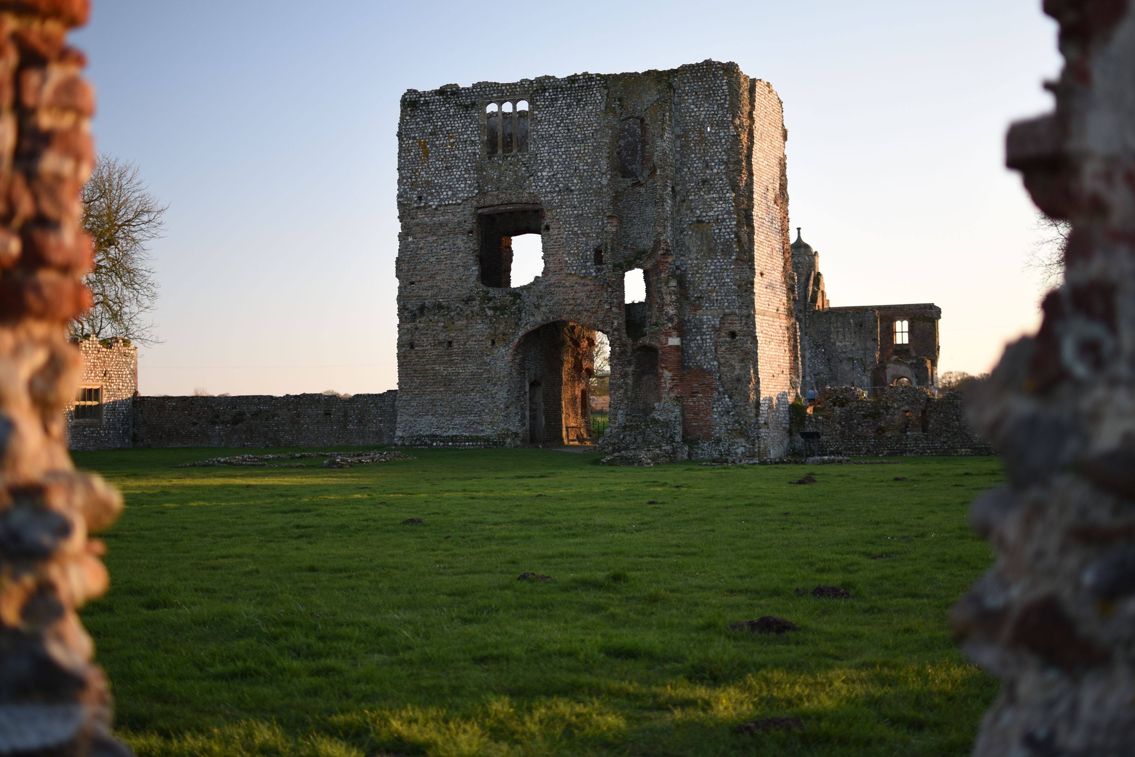 An ancient stone structure with multiple arches and a grassy field in the foreground.