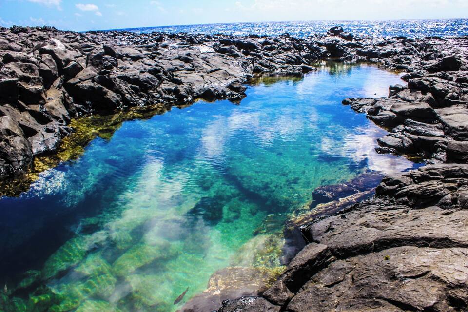 Uma costa rochosa com águas azul-claras refletindo o céu.