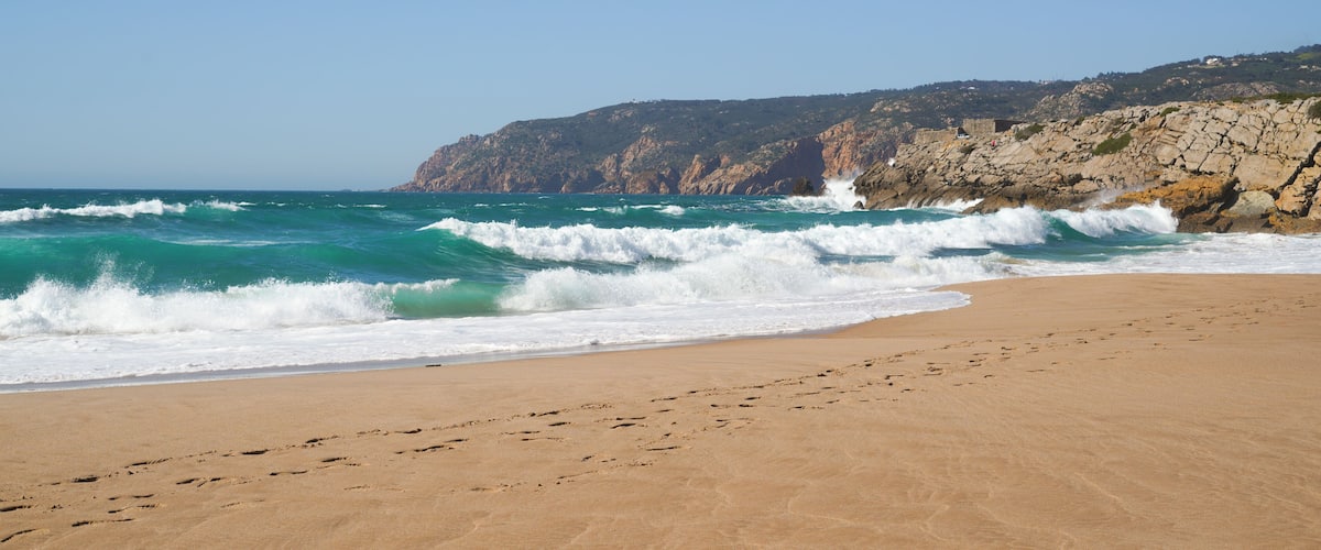 Waves on the empty  beach with mountains and rocks in the background, Guincho beach, Portugal