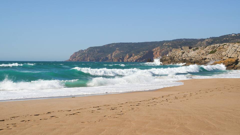 Waves on the empty beach with mountains and rocks in the background, Guincho beach, Portugal