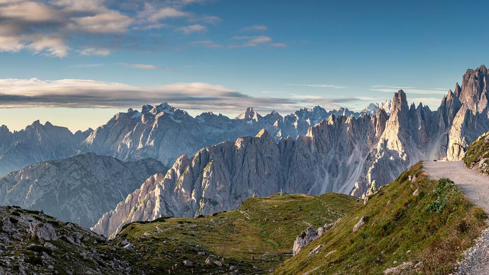 A mountain path with rocky terrain and snow-capped peaks.