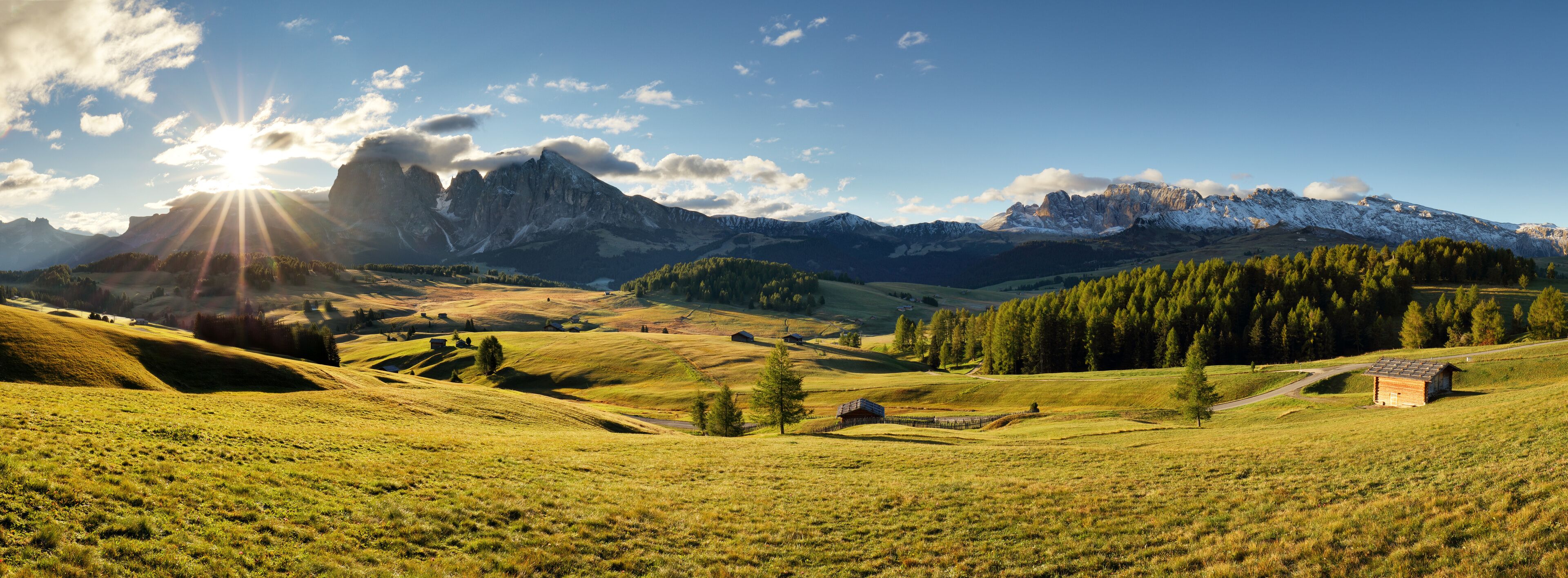 A mountainous landscape with a small cabin, rolling hills, and a clear sky.